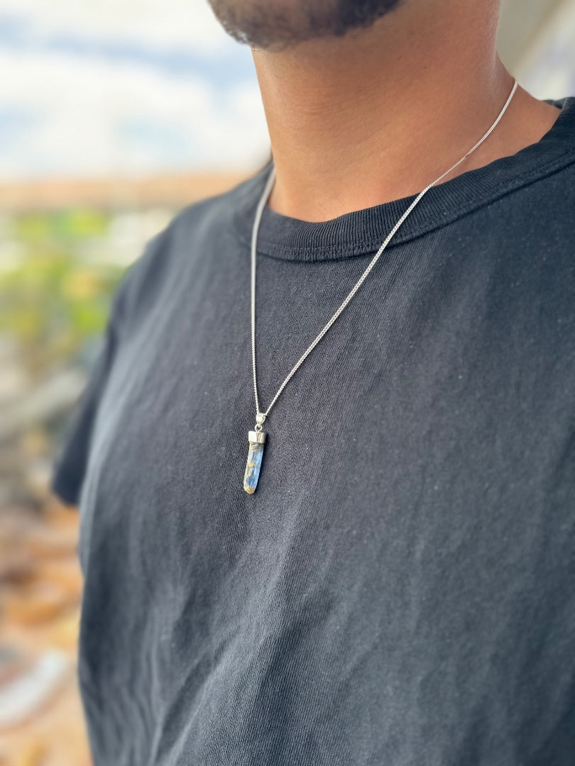 Person wearing a necklace with a pendant outdoors