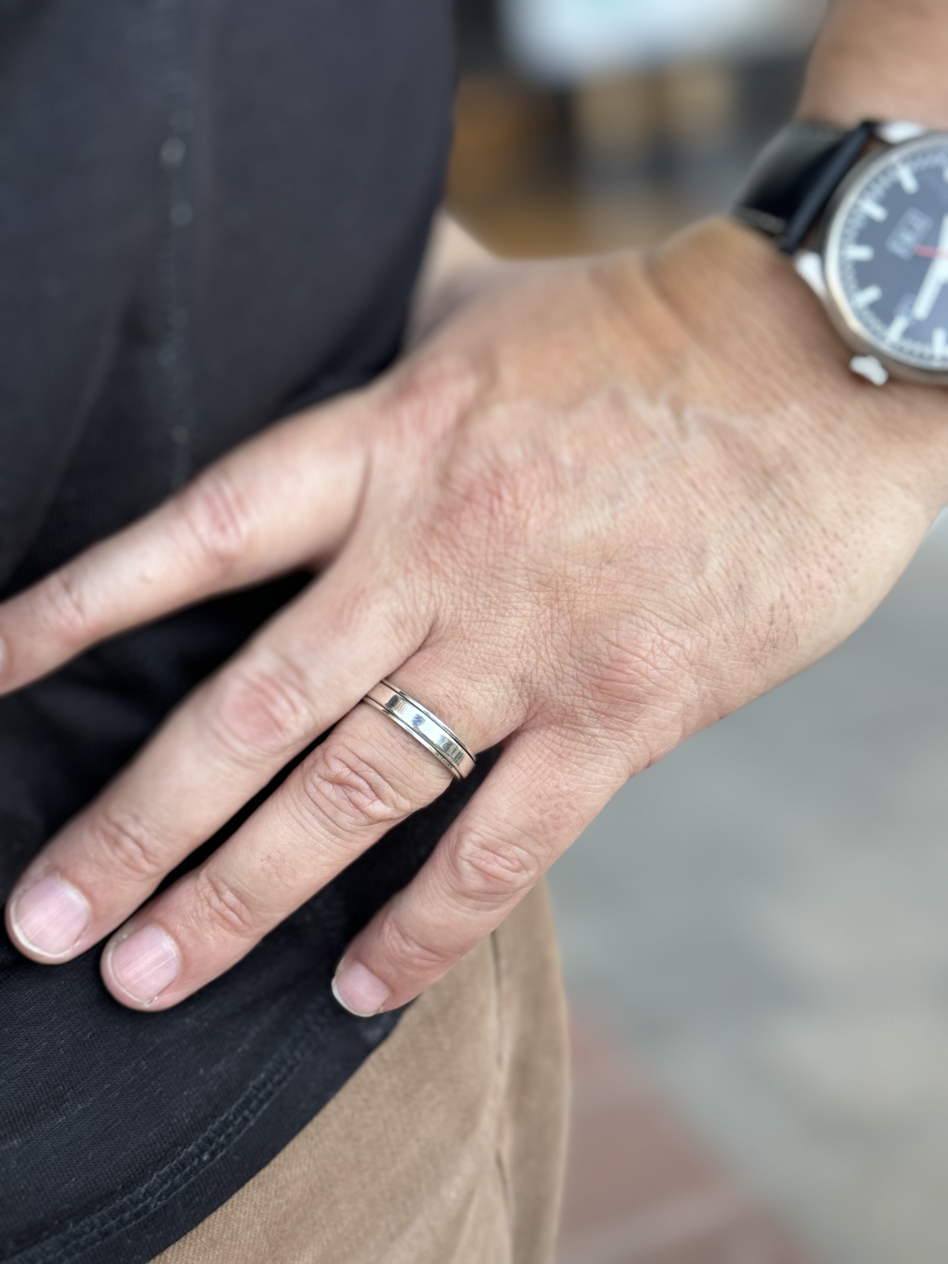 Hand wearing a silver ring with a blurred background