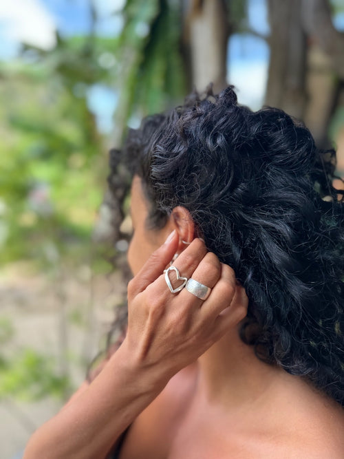 Person with textured hair wearing a silver ring outdoors