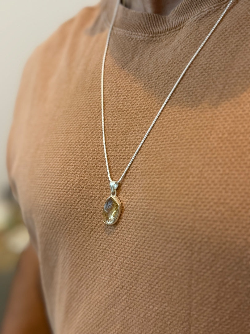 Necklace with a pendant worn by a person in a brown top