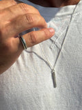 Hand wearing a silver ring with a necklace featuring a similar design.
