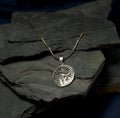 Silver pendant necklace on a dark stone surface