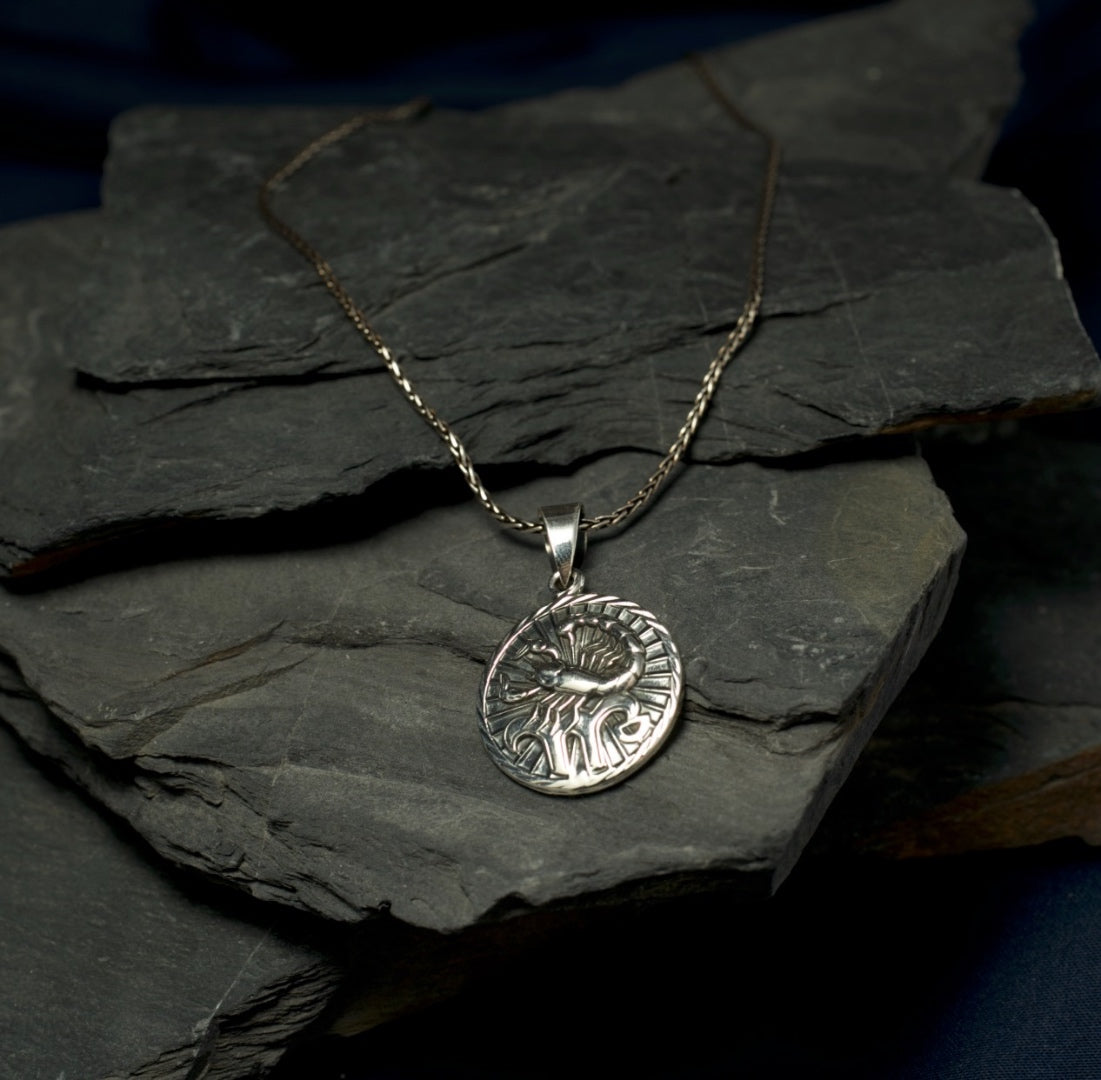 Silver pendant necklace on a dark stone surface