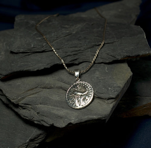 Silver pendant necklace on a dark stone surface