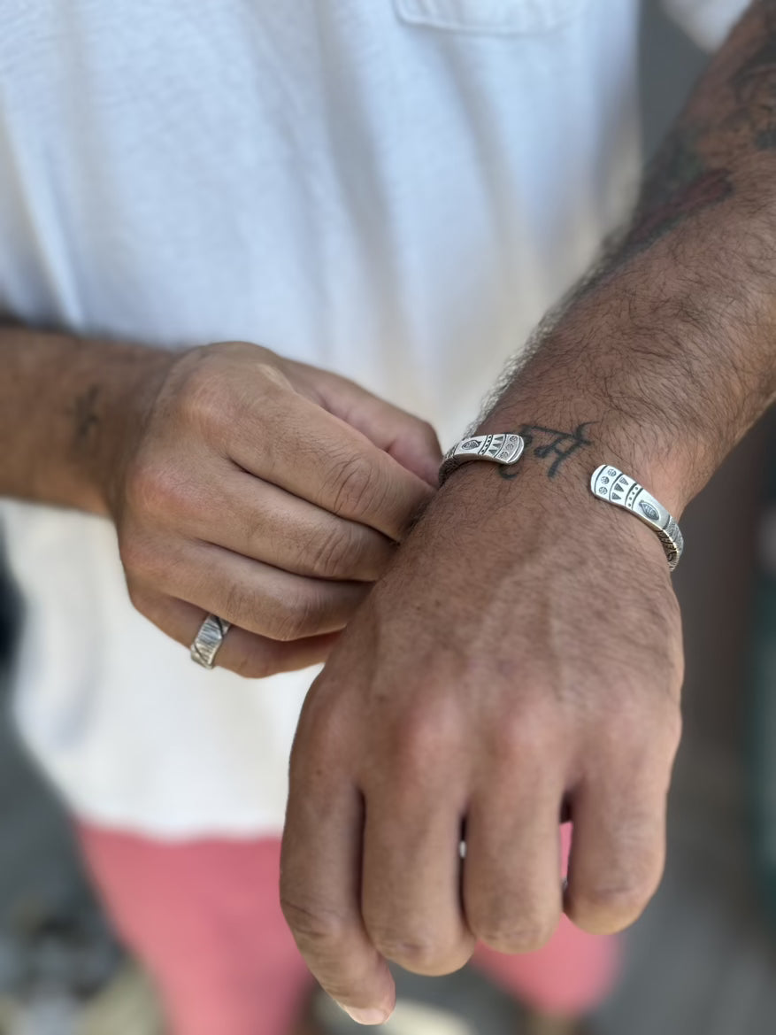 Close-up of a person's hands with rings on fingers, wearing a white shirt.