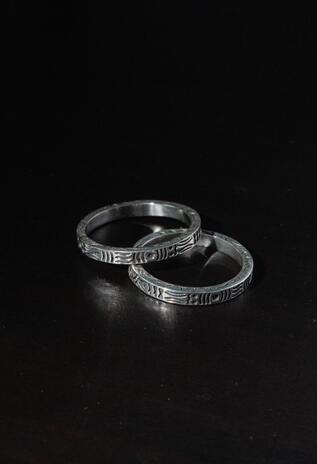 Two silver rings with intricate patterns on a black background