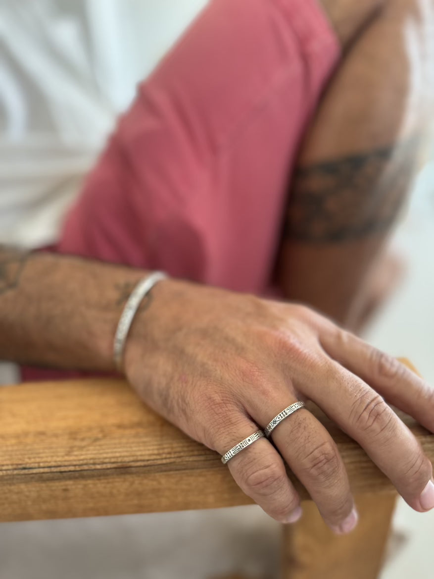 Close-up of a person's hand wearing two rings on a wooden surface