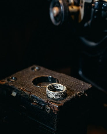 Silver ring on a textured brown surface with a dark background