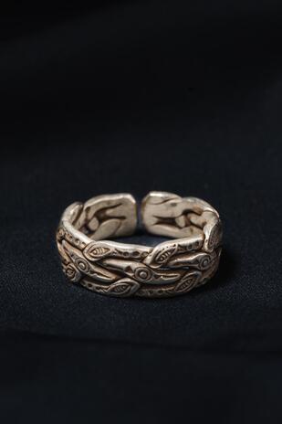Silver ring with intricate designs on a black background