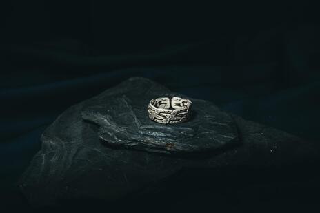 Silver ring on a dark stone surface with a dark background