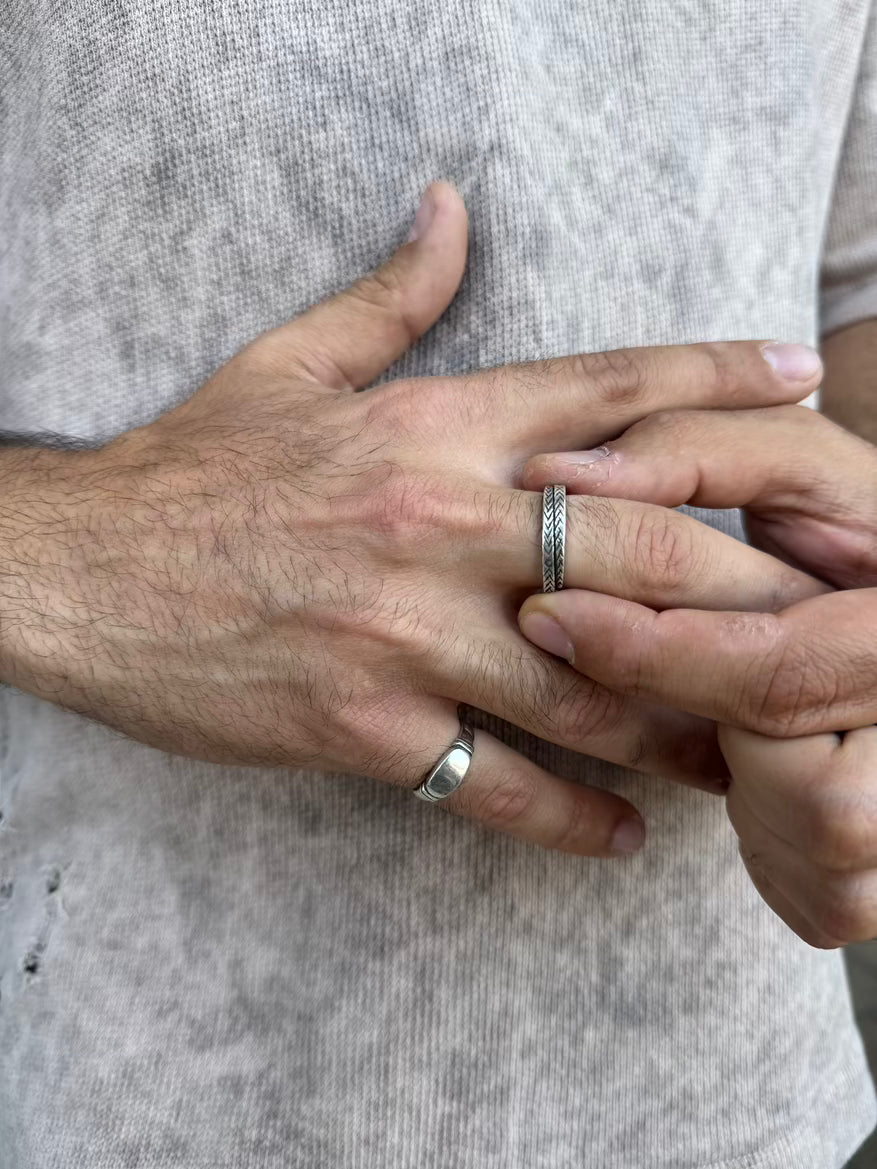 Two hands with silver rings on a neutral background