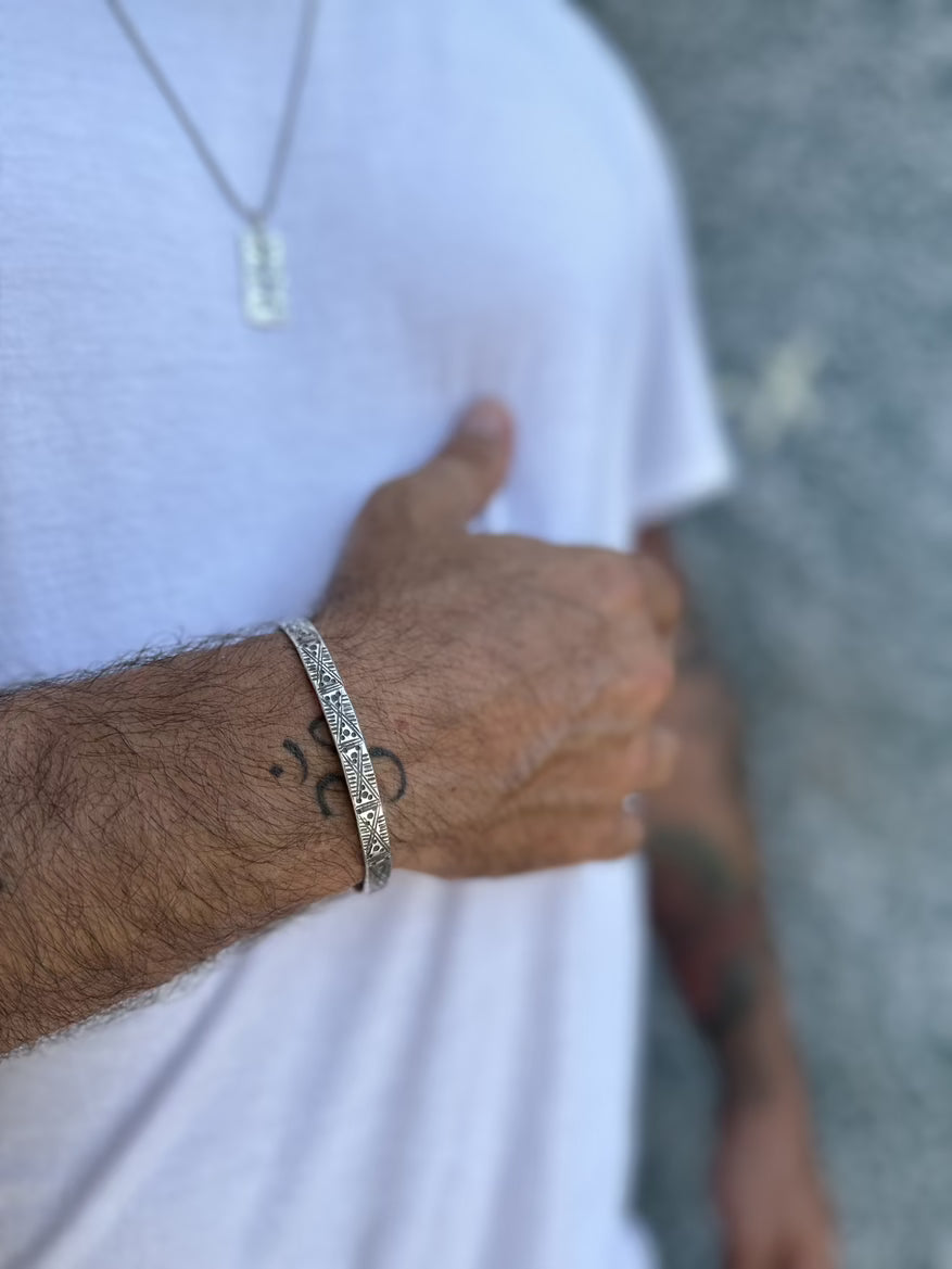 Close-up of a person's arm wearing a silver bracelet with a blurred background