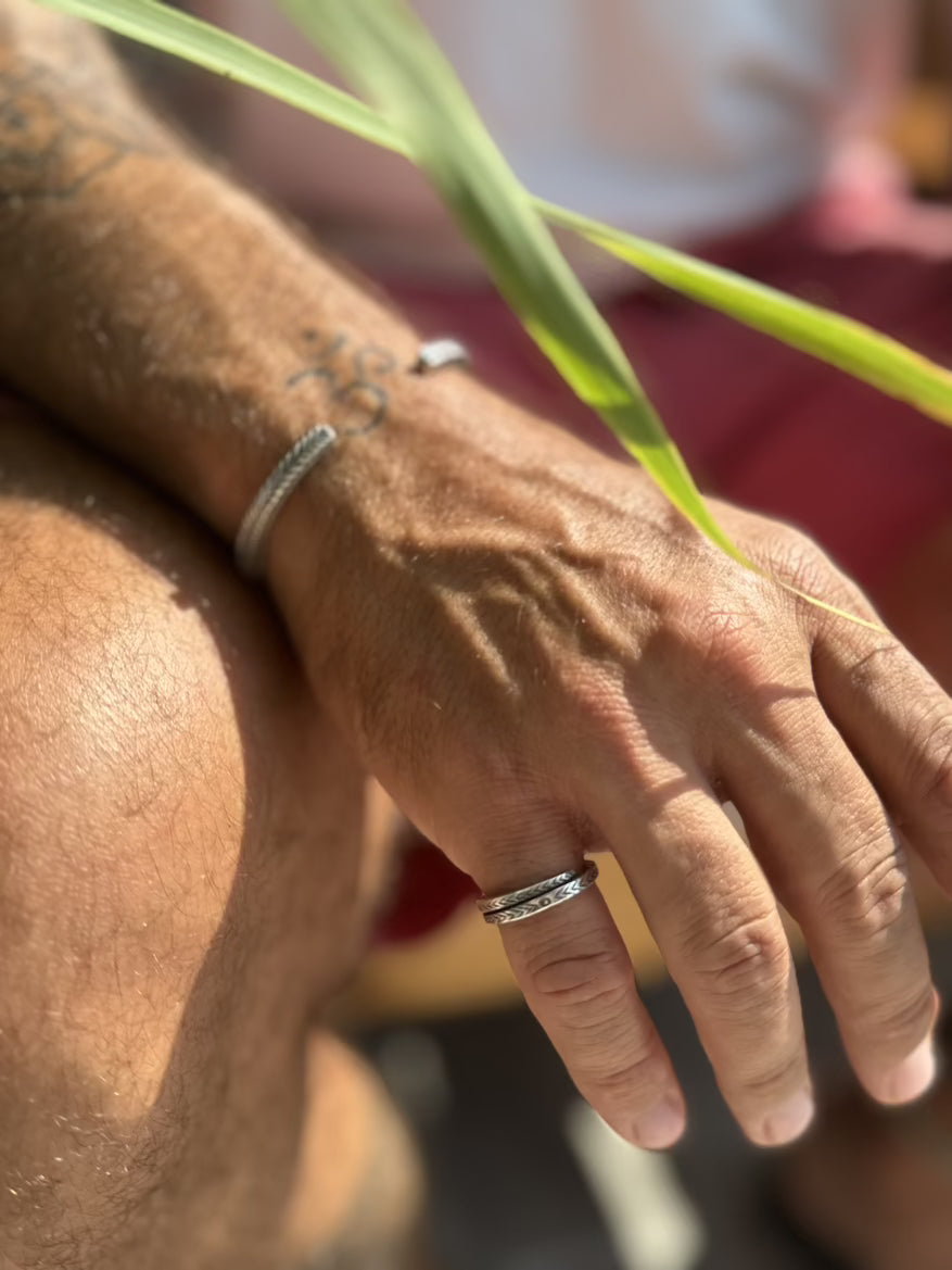 Close-up of a person's hand with multiple rings and tattoos, holding a plant.
