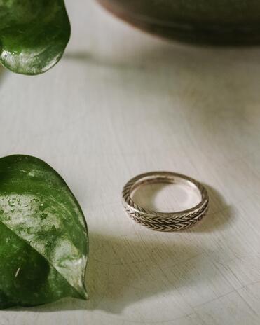 Silver ring on a wooden surface with a green leaf