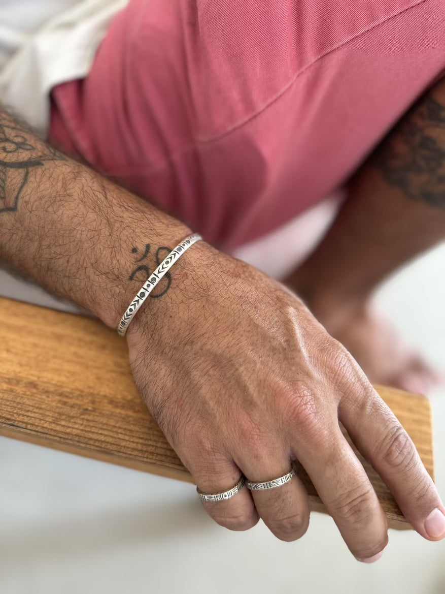 Hand with silver bracelets and rings on a blurred background