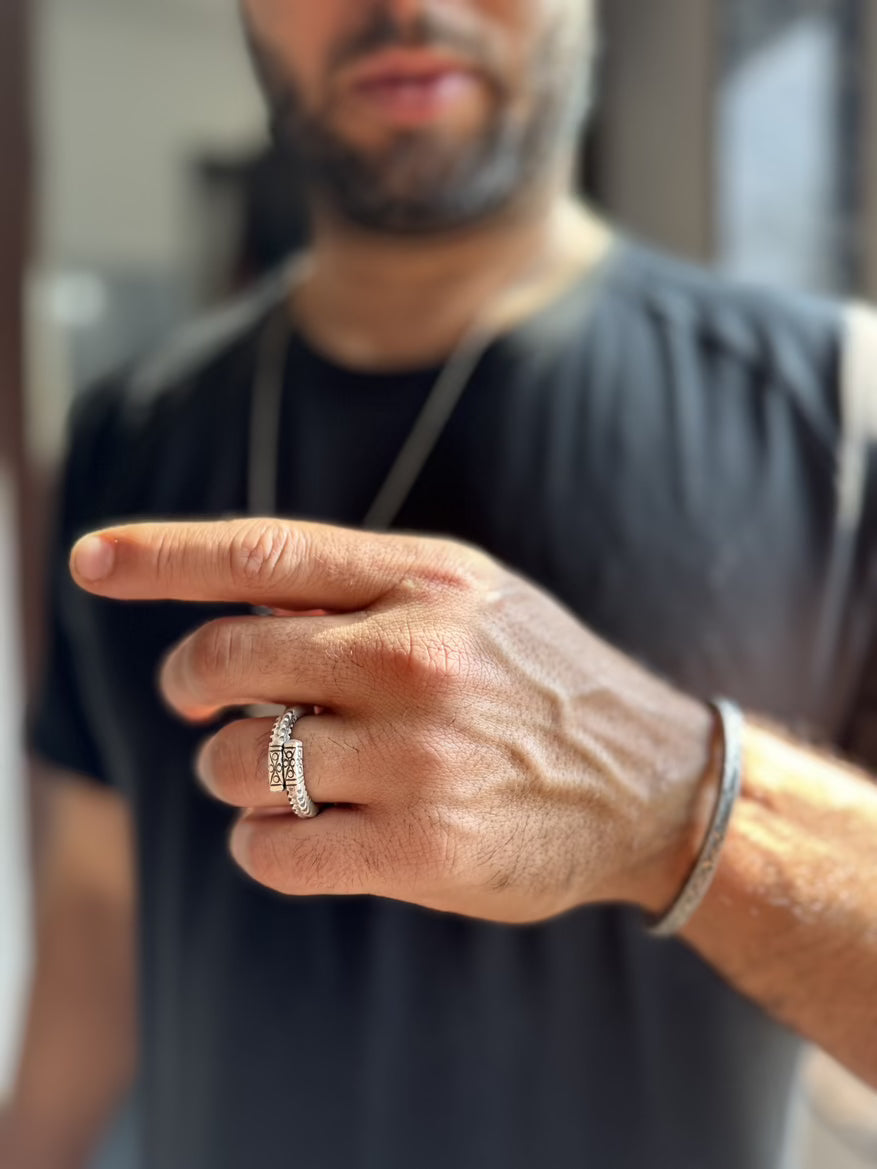Man wearing a silver ring on his finger with a blurred background
