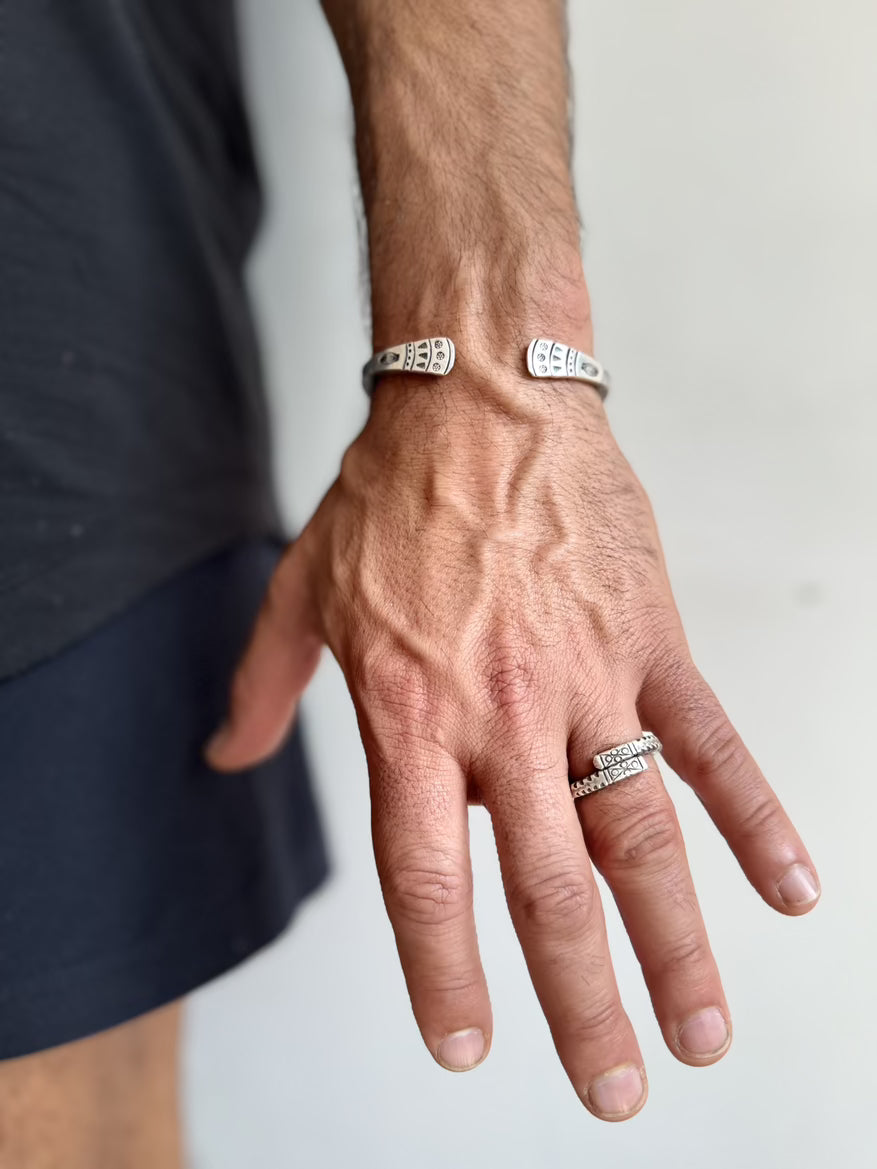 Hand wearing two silver rings with a plain background