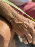 Close-up of a person's wrist with multiple bracelets and rings, wearing a gold bracelet.