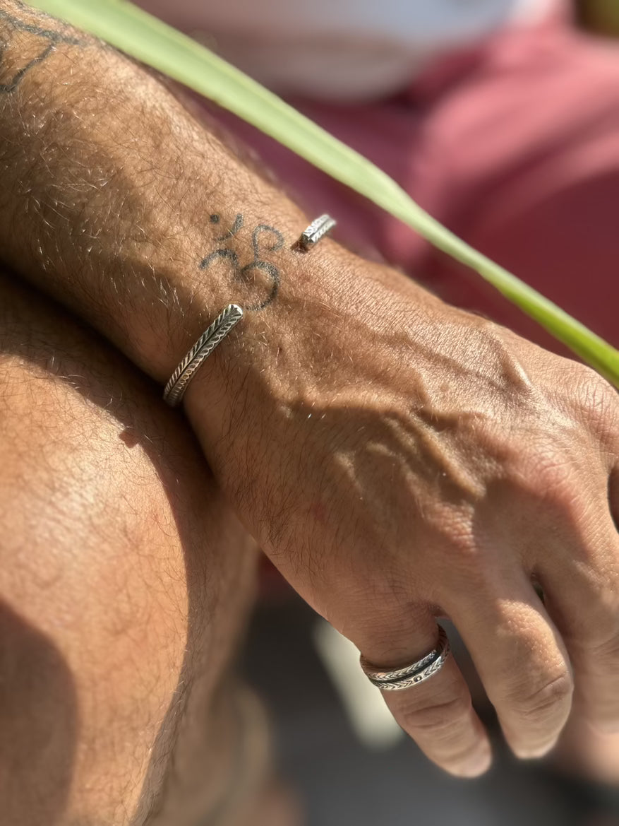 Close-up of a person's wrist with multiple bracelets and rings, wearing a gold bracelet.