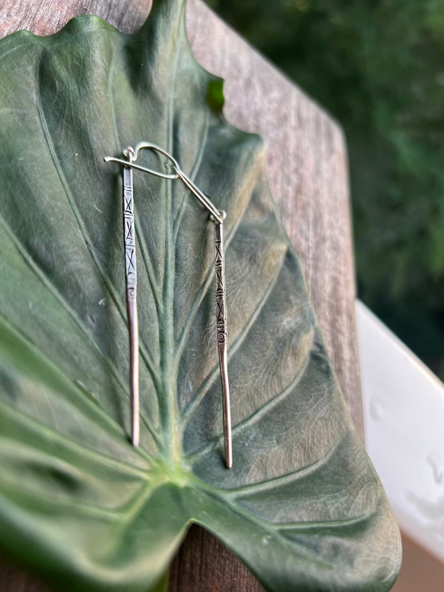 Silver earrings on a large green leaf