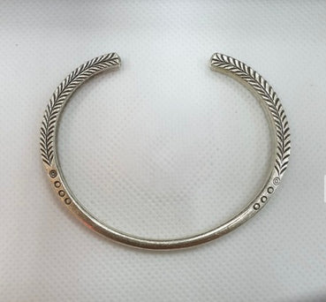 Silver necklace with leaf-like design on a white background