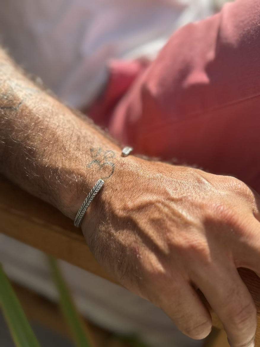 Close-up of a person's wrist with a bracelet and tattoo, blurred background