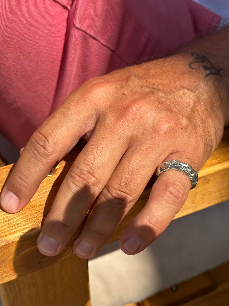 Hand with a silver ring on a wooden surface