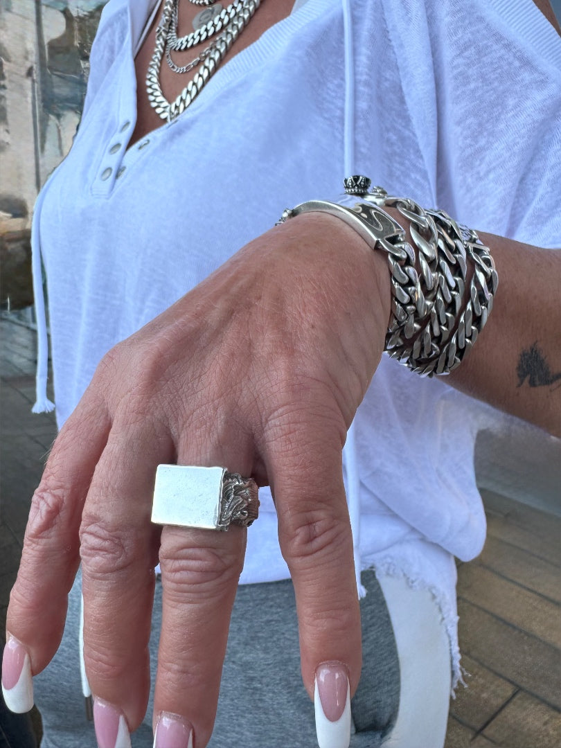 Close-up of a hand wearing a silver ring and bracelet against a blurred background
