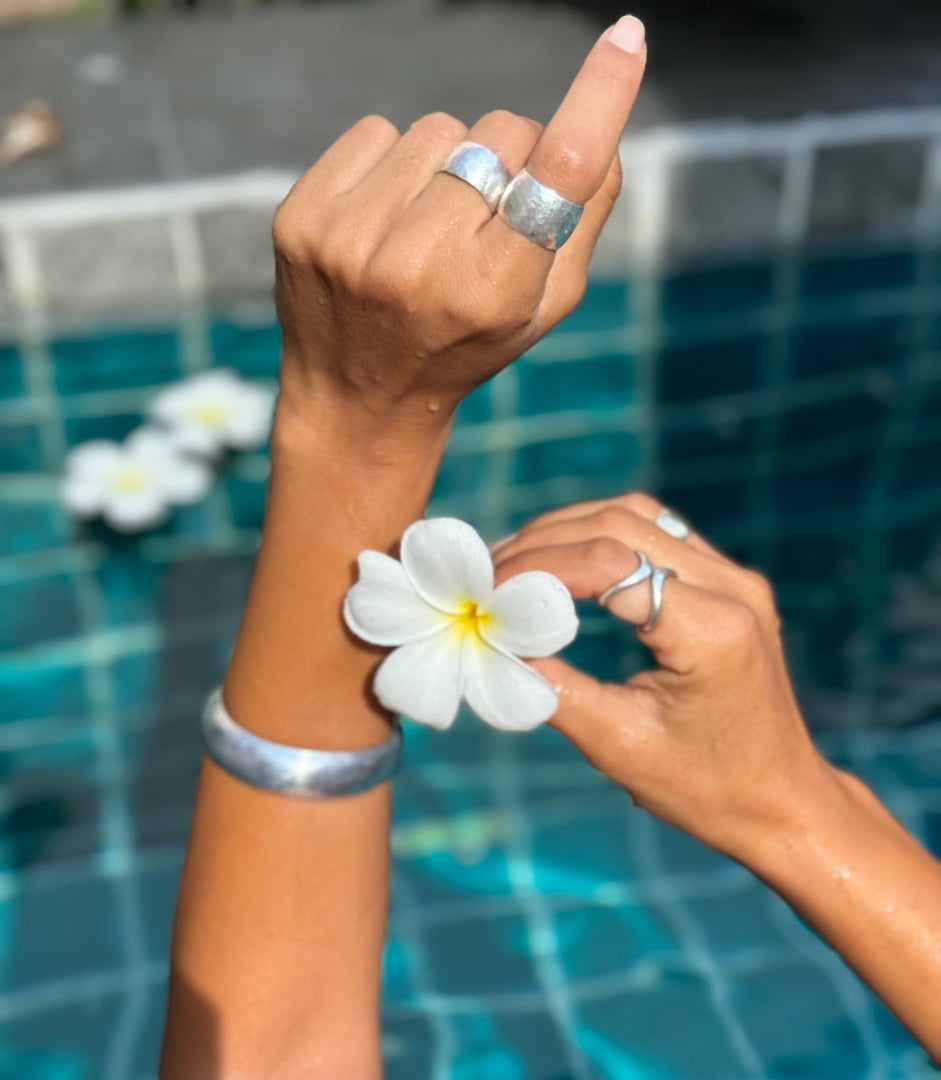 Person holding a white flower with a pool in the background