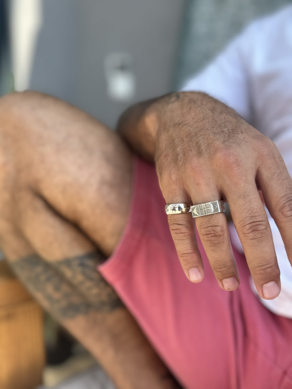Close-up of a hand wearing a silver ring with a blurred background