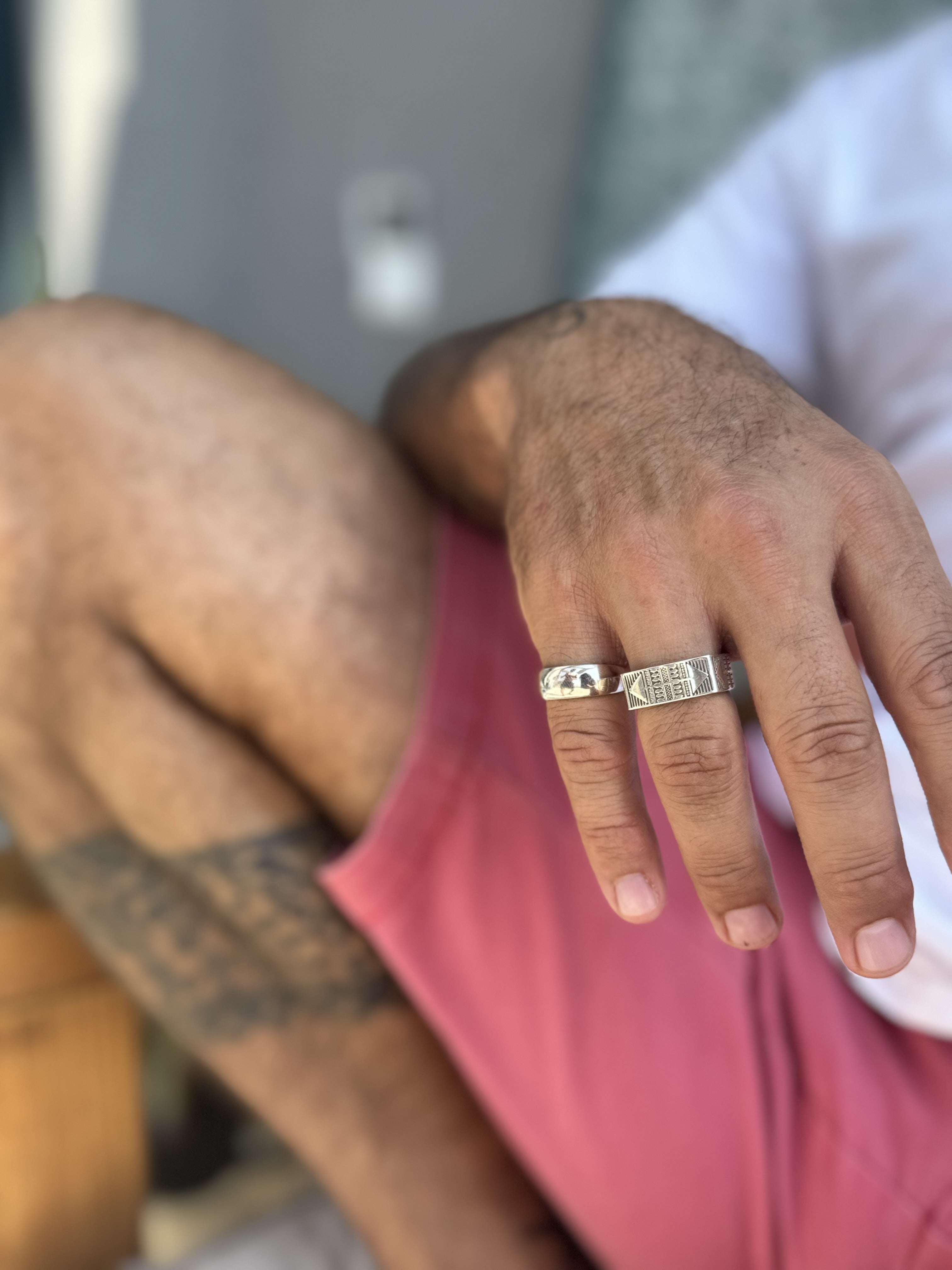 Close-up of a hand wearing a silver ring with a blurred background