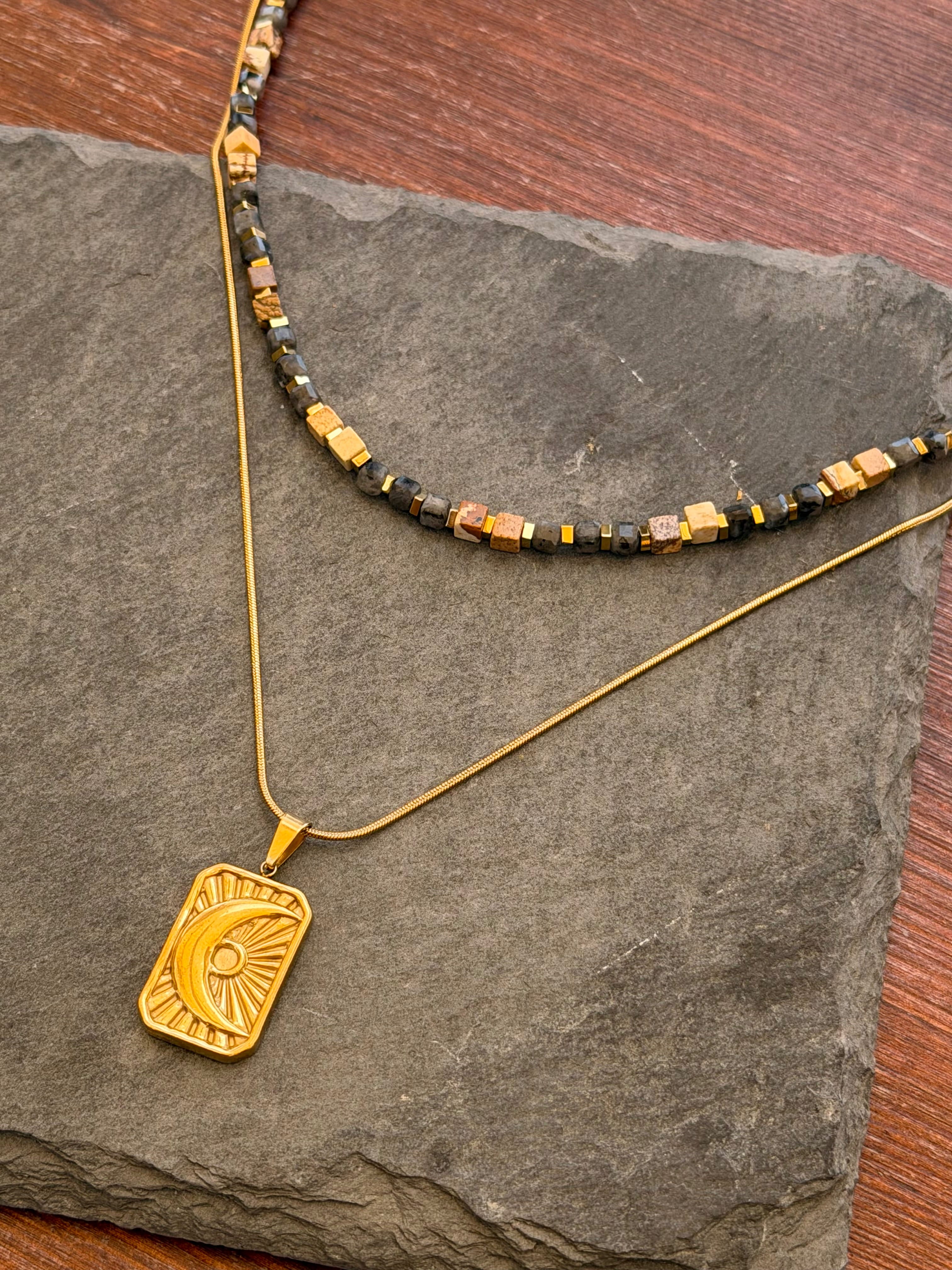 Gold necklace with a pendant on a stone surface