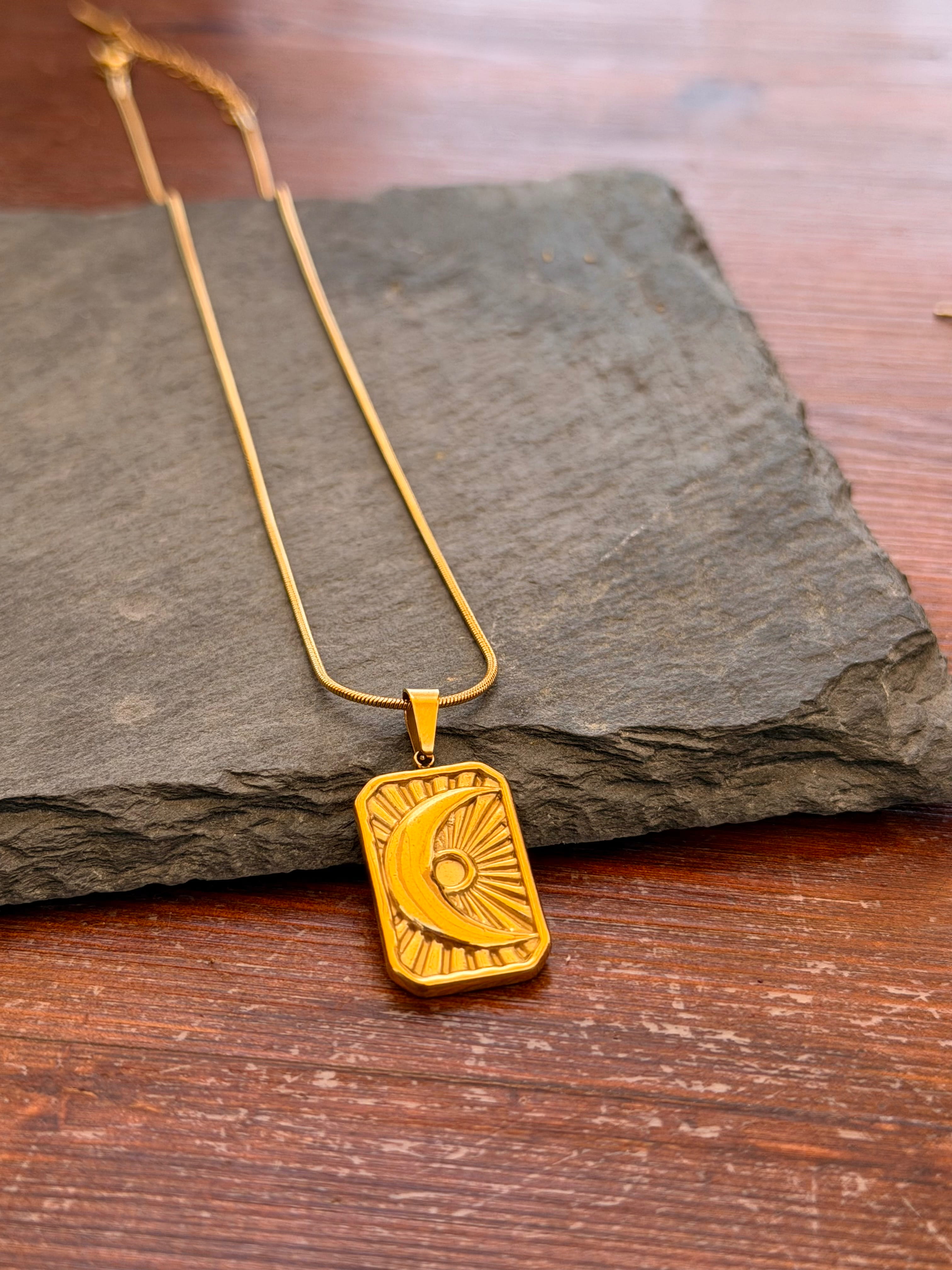 Gold pendant necklace on a dark stone surface