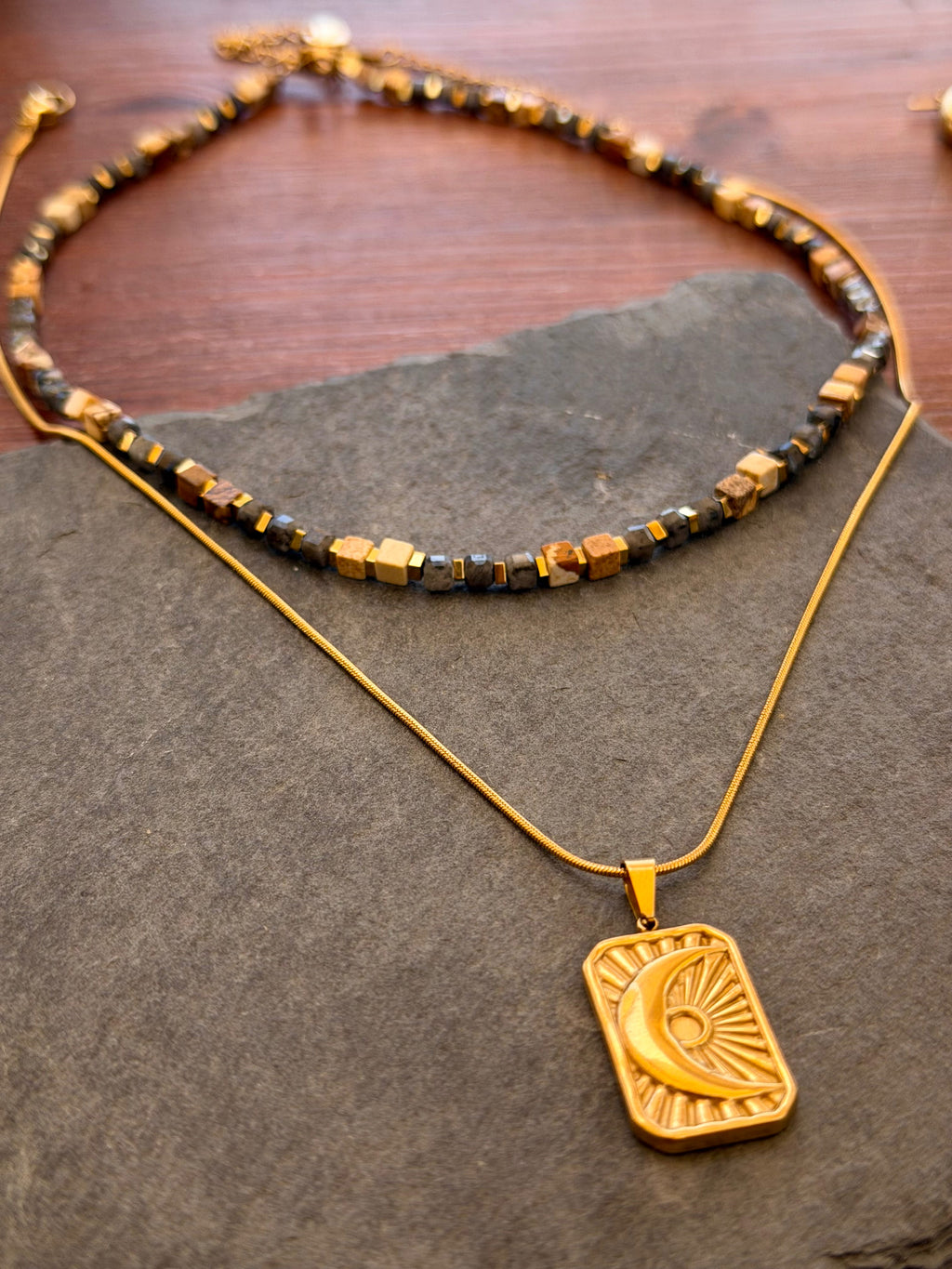 Gold necklace with a pendant on a stone surface