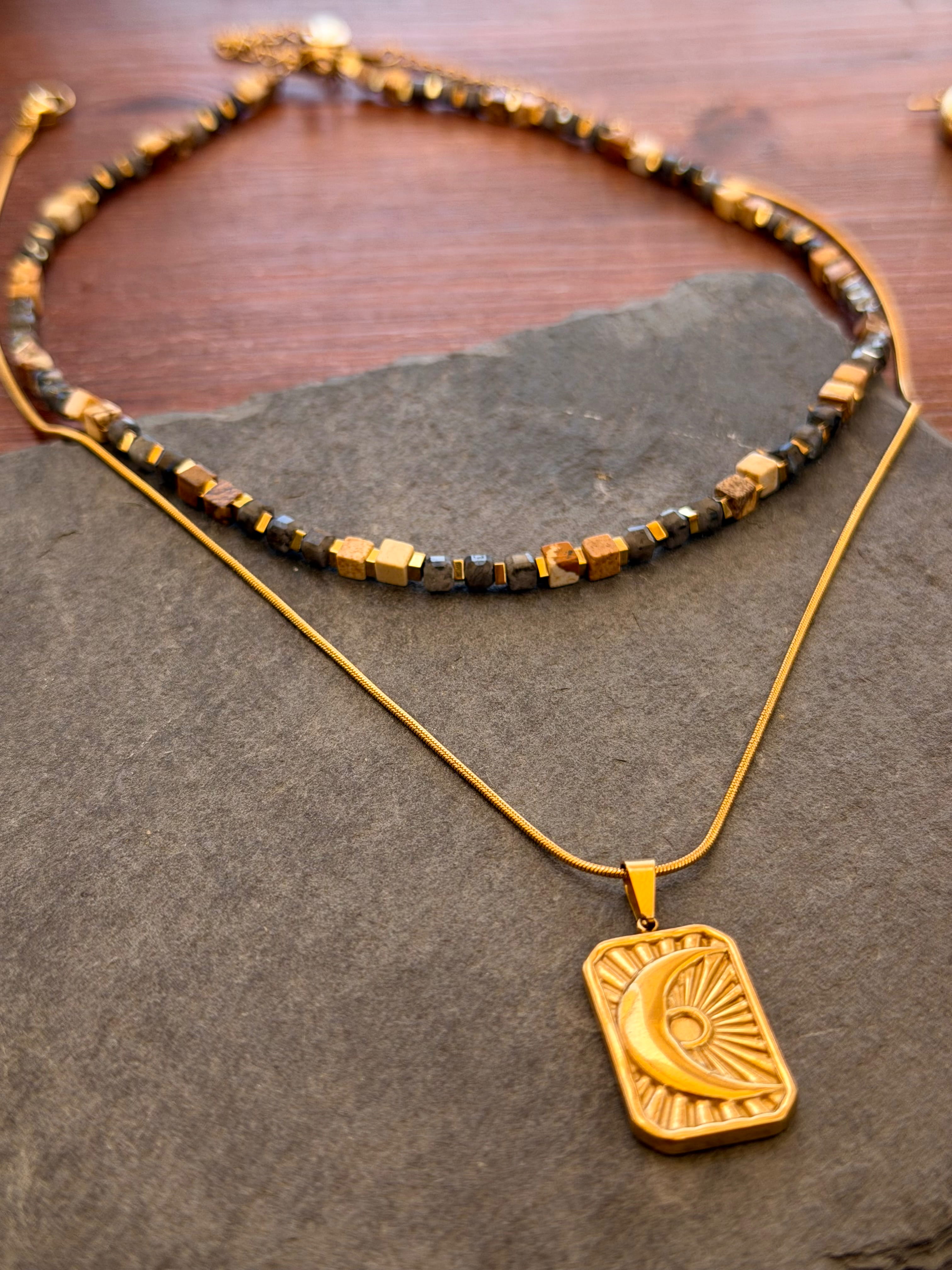Gold necklace with a pendant on a stone surface