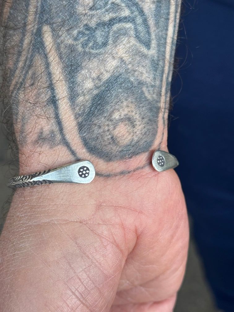 Close-up of a person's wrist with a silver bracelet featuring a geometric design.