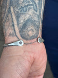 Close-up of a person's wrist with a silver bracelet featuring a geometric design.