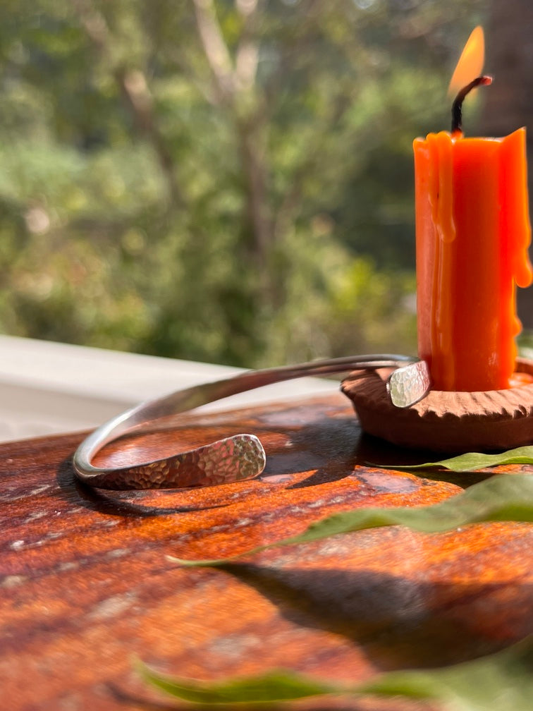 Close-up of a wooden bow with an orange nocking point and white fletching against a blurred green background.